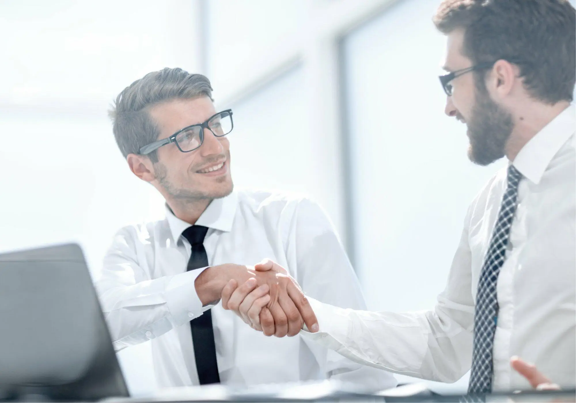 handshake-business-colleagues-sitting-their-desk-business-concept